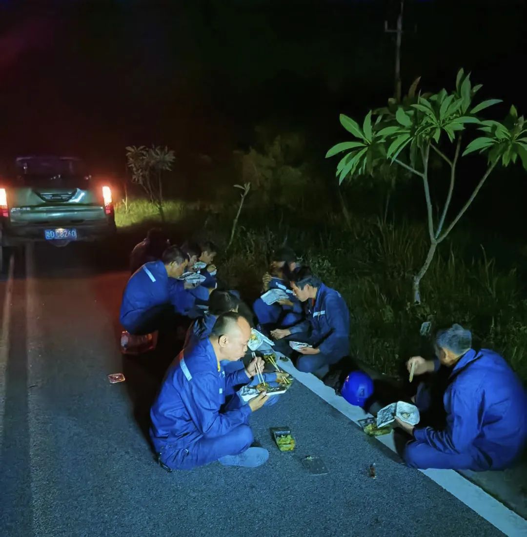 6月14日夜晚,东方供电局工作人员正对10千伏红兴线开展抢修作业,没来得及吃晚饭的抢修人员席地而坐,就着微弱的车灯,聚在一起享用了一顿“户外野餐”。(周志敏).jpg